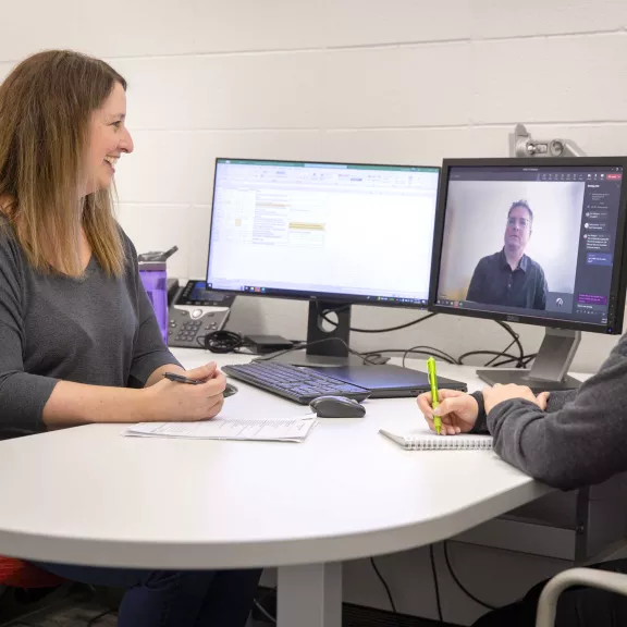 Two employees meeting with a client virtually.